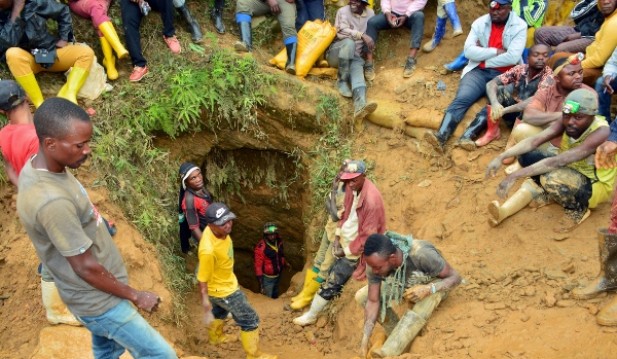 Congolese artisanal gold miners sit outside a mine-pit near Kamituga