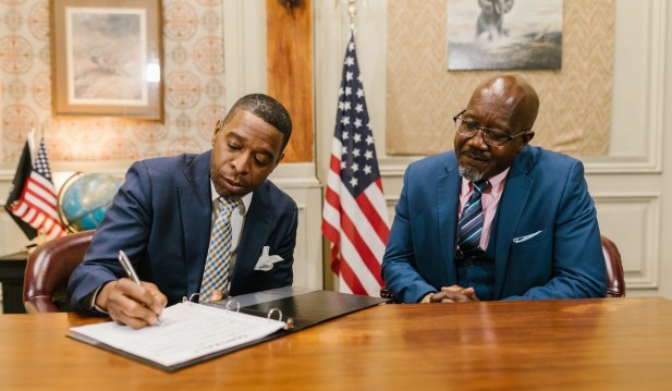 A Man Signing a Document beside his Colleague