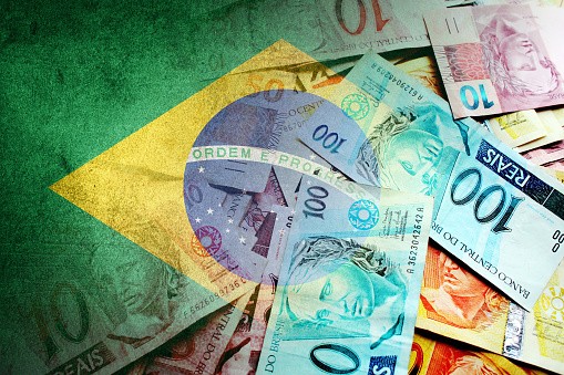 Brazilian reais cash bills and flag of Brazil - stock photo