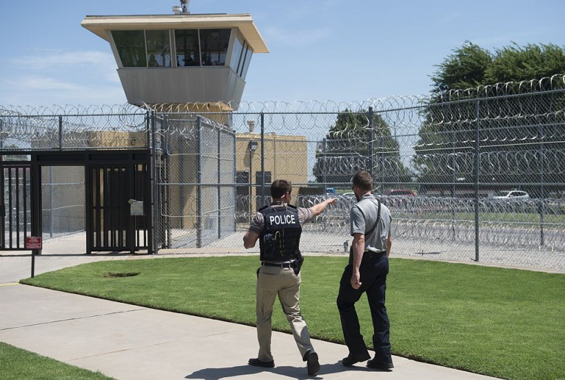 Police and a prison guard patrol the entrance of the El Reno Federal Correctional Institution in El Reno, Oklahoma