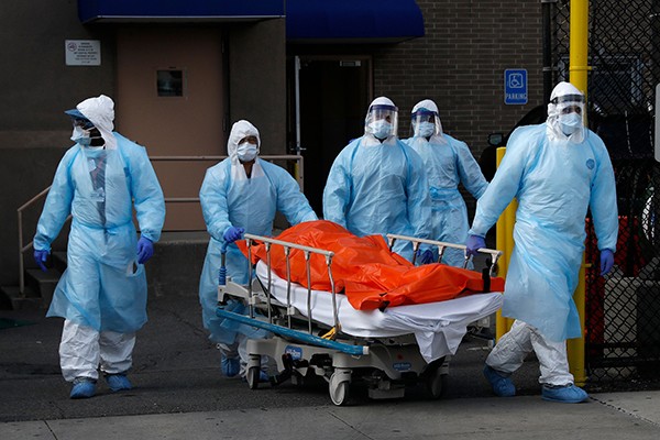 Healthcare workers wheel body of deceased person