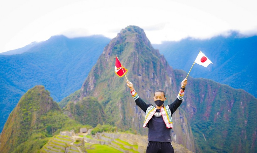 Japanese tourist Jesse Katayama holds a Peruvian and a Japanese flag after becoming the first tourist to visit the Inca citadel during the coronavirus disease (COVID-19) pandemic, in Machu Picchu